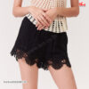 Detailed view of black shorts featuring intricate white crochet lace panels, highlighting the artistic design.