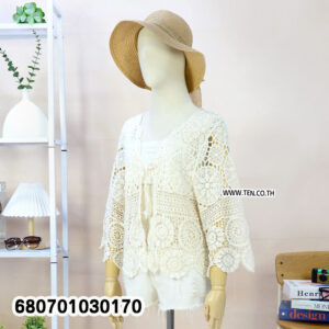 Woman’s boho crochet lace summer cardigan in cream, styled with shorts and straw hat.
