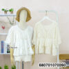 Casual white crochet lace blouse paired with shorts, displayed in a minimal setting.